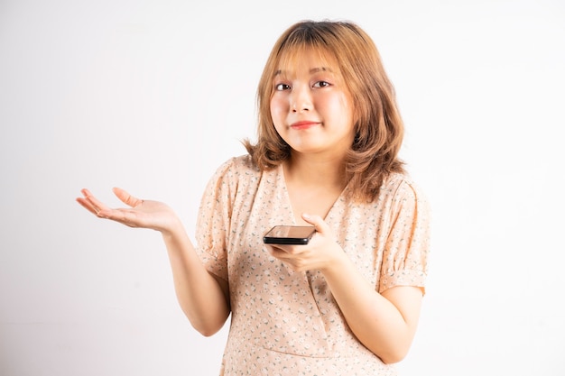 Молодая азиатская девушка держит телефон с выражениями и жестами на белом