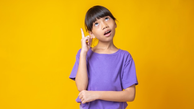 Молодая азиатская девушка в фиолетовой рубашке думает и указывает на идею