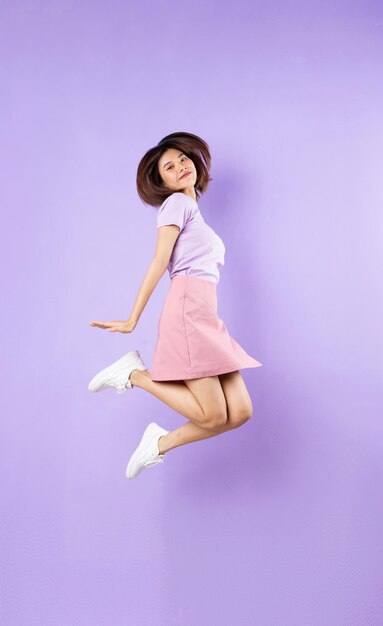 Young asian girl jumping up on purple background person