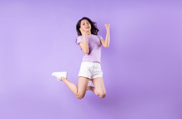 Young asian girl jumping up on purple background