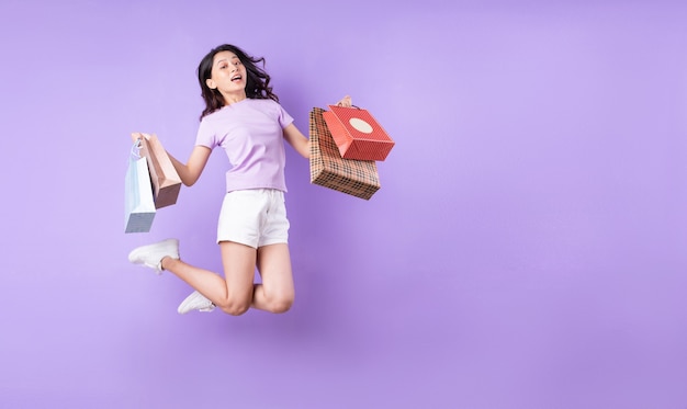 Молодая азиатская девушка прыгает на фиолетовом фоне