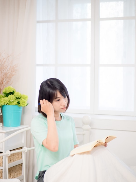 침대에서 책을 읽는 젊은 아시아 소녀