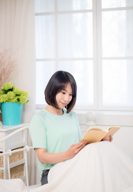 ベッドで本を読んでいる若いアジアの女の子