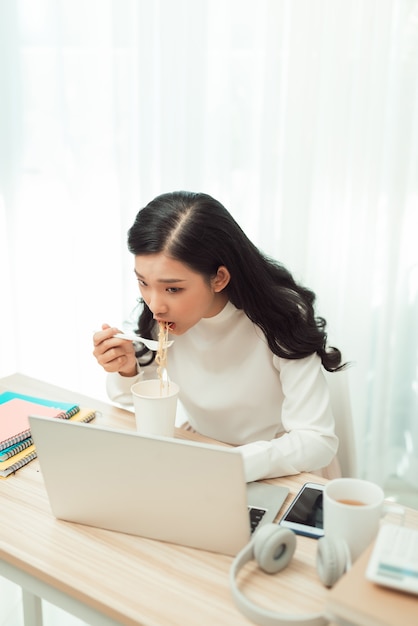 机の上に座っている若いアジアの女の子は残業