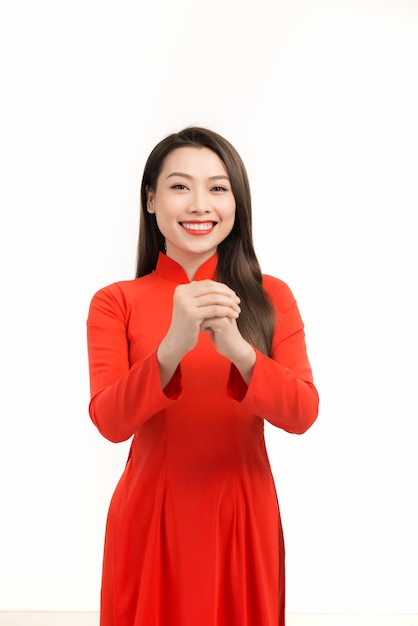 Young Asian girl in traditional ao dai dress smiling and greeting, celebrating Lunar New Year or spring festival