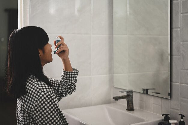 Young Asian girl using asthma inhaler for inhalation treatment of respiratory diseases.