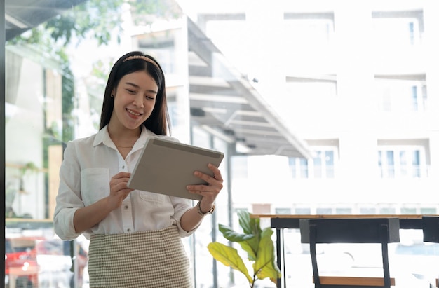 Giovane ragazza asiatica che utilizza un supporto per tablet digitale nell'ufficio a casa