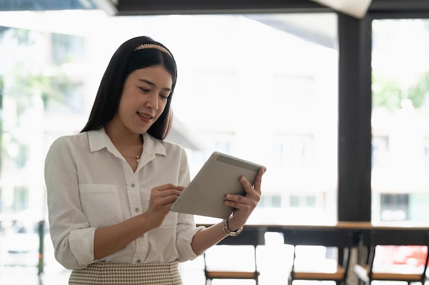 Молодая азиатская девушка с цифровым планшетом в домашнем офисе
