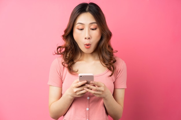 Young asian girl using the phone on pink