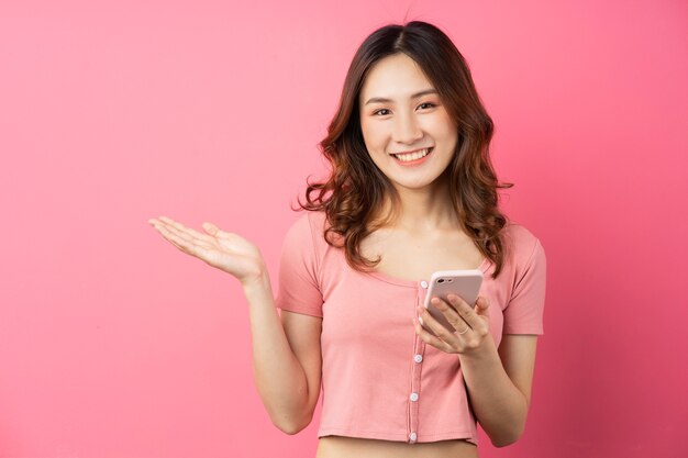 Young asian girl using the phone on pink