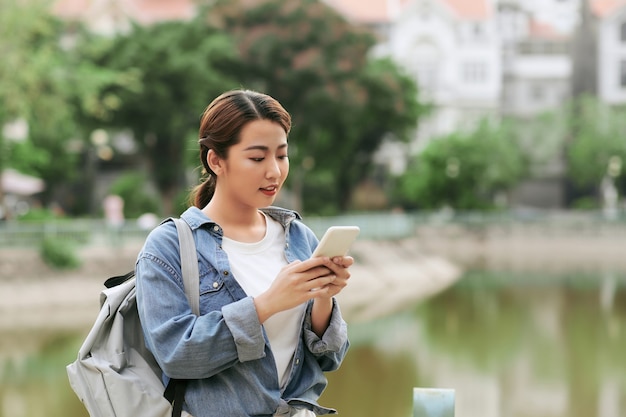 정원에서 스마트 휴대 전화를 사용 하여 젊은 아시아 소녀