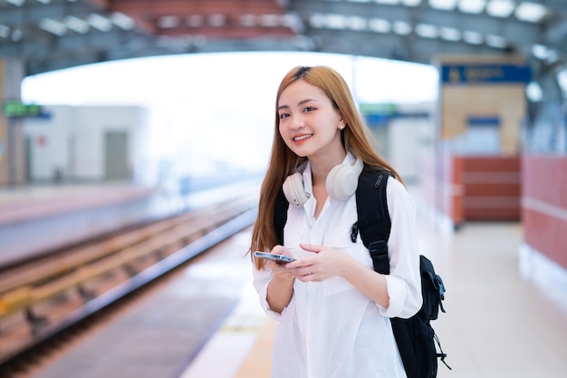 Молодая азиатская девушка ждет поезд на вокзале