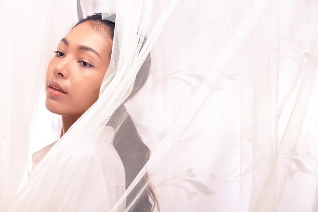 Young Asian Girl wakes up by wind and Sun light from curtain window