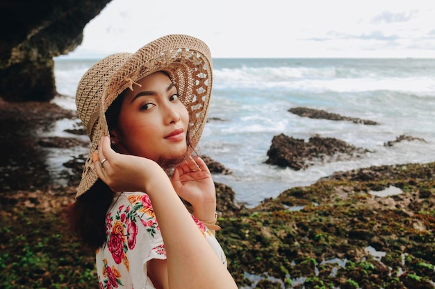 A young Asian girl wearing beach hat is relaxing on the blue sky beach at Gunungkidul Indonesia