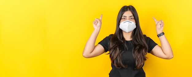 Young asian girl wearing a medical face mask in casual clothing isolated on yellow background