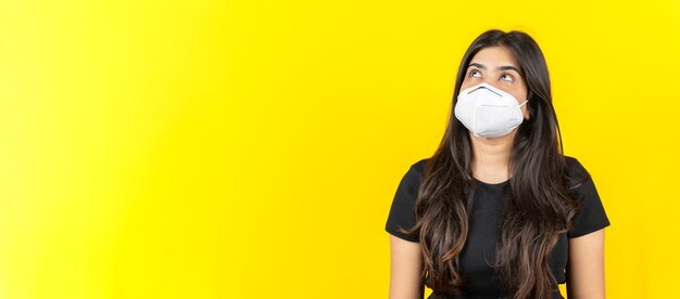 Young Asian girl wearing a medical face mask in casual clothing isolated on yellow background