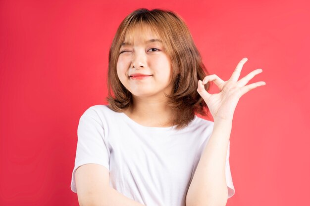 Young asian girl with cheerful gestures and expressions on pink