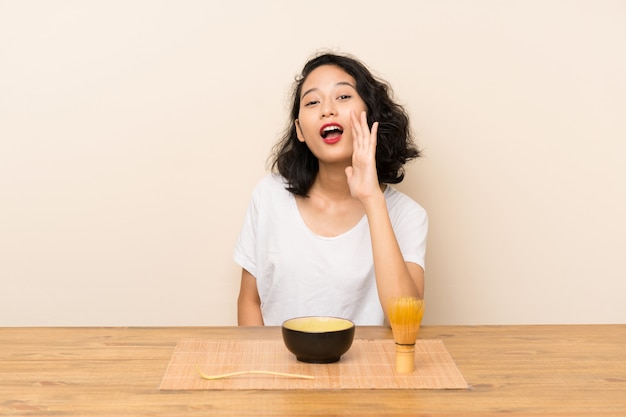 口を大きく開けて叫んでお茶抹茶を持つ若いアジアの女の子