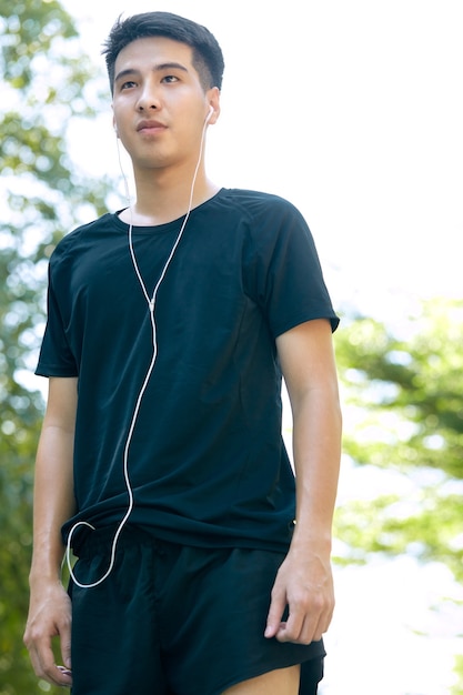 A young Asian happy cheerful smiling man during morning jogging outdoors. Fitness, sport, exercising crossfit, and workout concept.