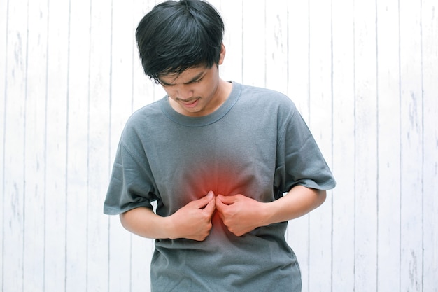 젊은 아시아 인은 위산 역류로 인해 가슴 중앙에 타는듯한 느낌의 증상이 있습니다.
