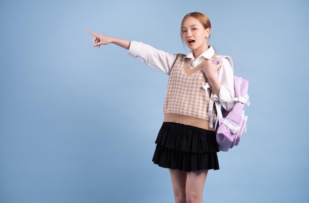 Young Asian high school girl on blue background