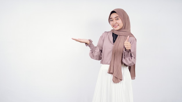 Young asian hijab woman pointing up blank on right side and okey isolated on white background