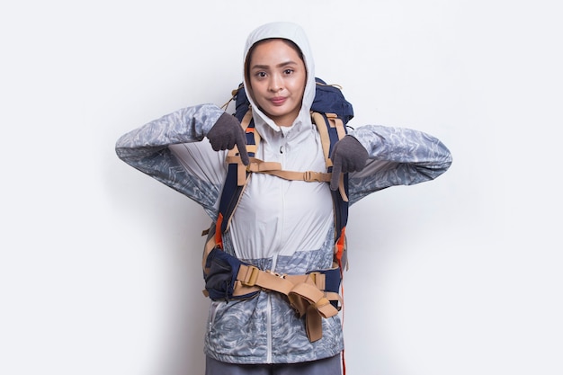 Young asian hiker woman with backpack pointing finger on empty space on white background