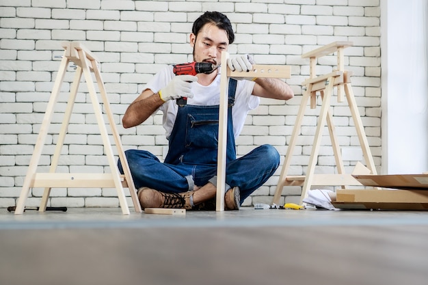 핸디맨으로 일하는 젊은 아시아 힙스터 남자, 장비가 있는 나무 테이블 조립, 가정 DIY, 셀프 서비스 및 취미에 대한 개념,