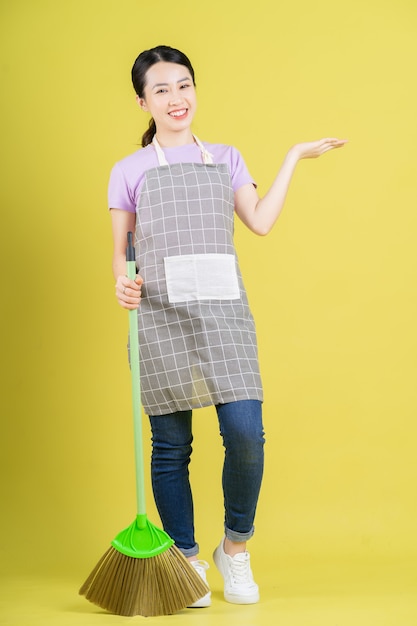 Photo young asian housewife posing on yellow background