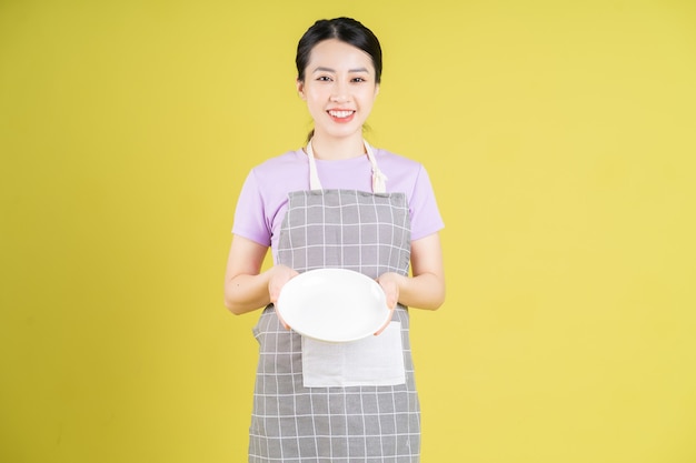 Young Asian housewife posing on yellow background