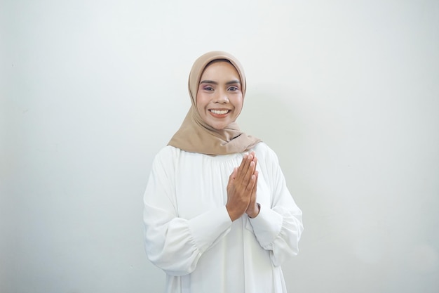 Young Asian Islam woman wearing headscarf gives greeting hands at with a big smile on her face