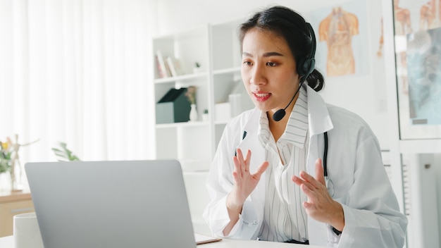 Young asian lady doctor in white medical uniform with stethoscope using computer laptop