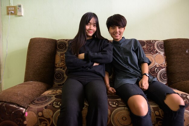 Young Asian lesbian couple sitting on the sofa together