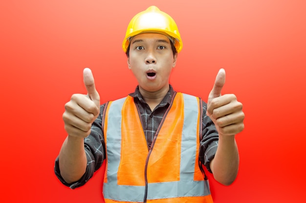 写真 アジアの若い男性の建設労働者またはエンジニアが、幸せそうに微笑み、褒め言葉として親指を上げます。