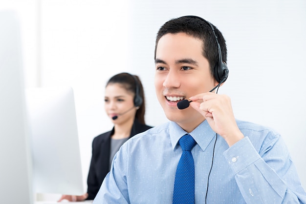 Young Asian male telemarketing customer service agent working in call center