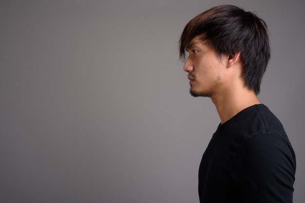 Young Asian man against gray wall