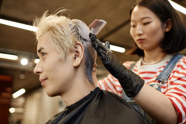 Photo young asian man in beauty salon with hairstylist bleaching or dyeing hair