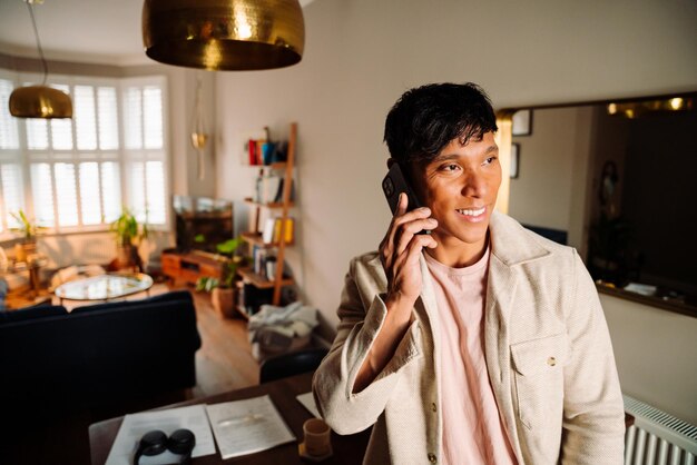 Young asian man on cellphone at home office