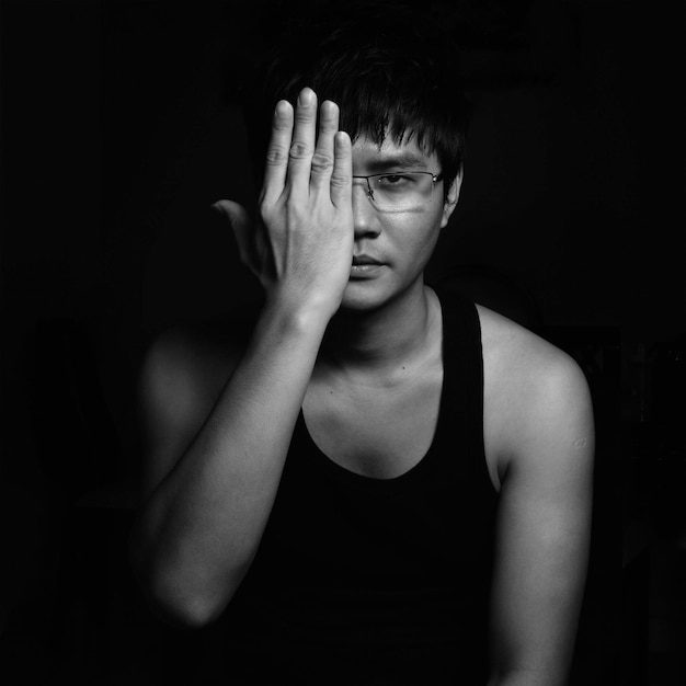 Young Asian man covering his face with a palm Black and White