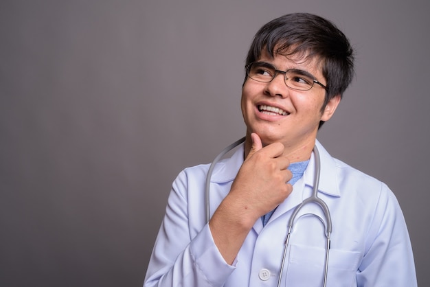 Young Asian man doctor against gray wall