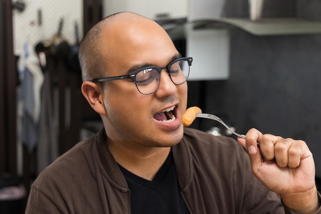 A young Asian man eating breakfast, he eats pork sausage. He poked it with a fork and bit his gut and chewed deliciously. Slow motion and movement short