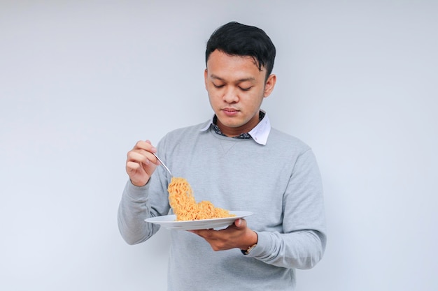 若いアジア人男性は麺を楽しむランチコンセプトを食べる