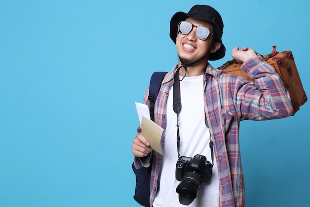 Foto giovane asiatico in occhiali con un sorriso positivo viaggia all'estero, tenendo biglietti e borsa
