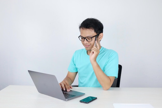 Young Asian man feeling happy and smile when work laptop on table Indonesian man wearing blue shirt