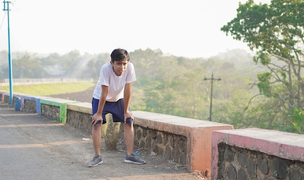 Young asian man having streaching before jogging in the morning