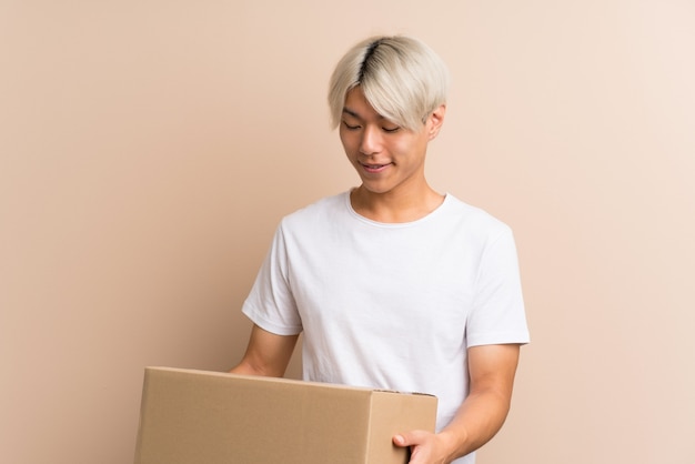 Photo young asian man holding a box to move it to another site