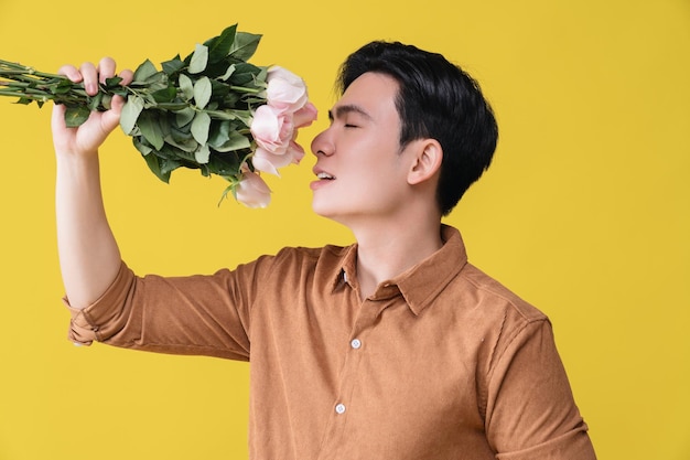 Young Asian man holding flower on background