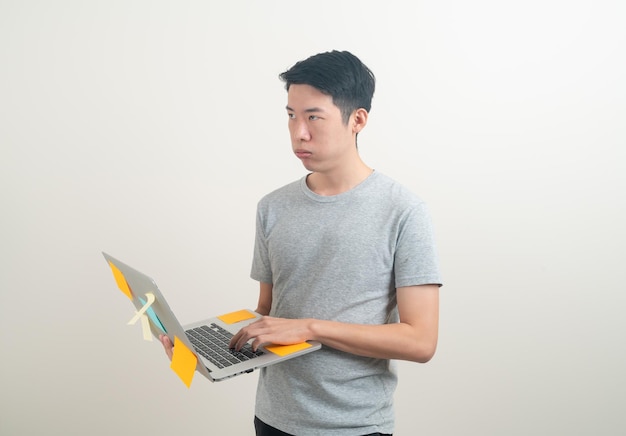 스트레스를 받는 얼굴로 노트북을 들고 있거나 흰색 배경에서 열심히 일하는 젊은 아시아 남자