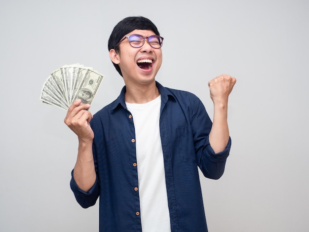 Young asian man holding money show fist up apreeciate happy about earn money