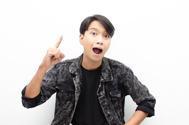 A young Asian man is looking surprised while pointing his finger upward. great idea concept.